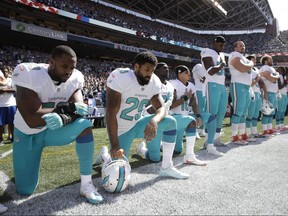 In this Sept. 11, 2017 file photo, from left, Dolphins players kneel during the singing of the national anthem before an NFL game against the Seahawks in Seattle.