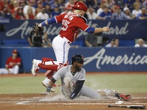 Tigers' Niko Goodrum scores past Blue Jays' Russell Martin, left, during fifth inning MLB action in Toronto, Sunday, July 1, 2018.