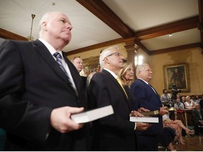 Doug Ford (right) is sworn in as premier of Ontario during a ceremony at Queen's Park in Toronto on Friday, June 29, 2018. Cabinet ministers Jim Wilson (left to right), Vic Fedeli and Christine Elliott look on.