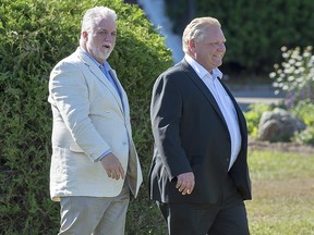 Quebec Premier Philippe Couillard, left, and Ontario Premier Doug Ford walk across the lawn in St. Andrews, N.B. on Thursday, July 19, 2018. (THE CANADIAN PRESS/Andrew Vaughan)