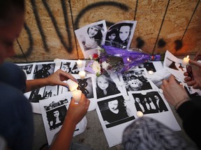 People light candles and leave photos of 18-year-old victim Reese Fallon at a memorial remembering the victims of a shooting on Sunday evening on Danforth, Ave. in Toronto on Monday, July 23, 2018.