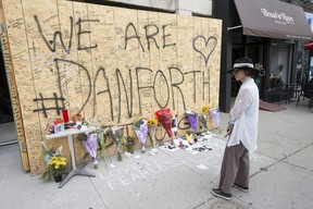 A woman stands at the memorial on Danforth Ave. just east of Logan Ave. on Tuesday. Craig Robertson/Toronto Sun