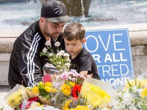 Police officer Norm Leung, a first responder during Sunday's Danforth Ave. shooting, brought his son Kai, 4, to pay their respects to the victims on Tuesday (Craig Robertson/Toronto Sun)