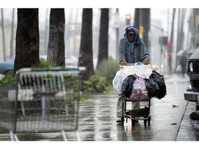 A homeless man pushes his belongings down Sunset Blvd. on a rainy afternoon in Los Angeles, California 18 October 2004.