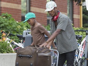 A father and his son drag luggage to an awaiting taxi at a Humber College on Aug. 9. (Stan Behal, Toronto Sun)
