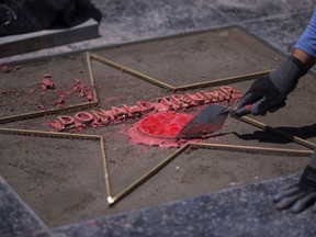 In this photo taken on July 25, 2018, workers replace the Star of U.S. President Donald Trump on the Hollywood Walk of Fame after it was destroyed by a vandal.  (DAVID MCNEW/AFP/Getty Images)