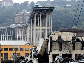 A picture taken on August 14, 2018 shows vehicles standing on a part of a giant motorway bridge after a section collapsed earlier in Genoa.  (Photo by ANDREA LEONI/AFP)