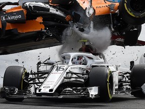 McLaren's Spanish driver Fernando Alonso (TOP) crashes ontop of Sauber F1's Monegasque driver Charles Leclerc (C/16) during the first lap of the Belgian Formula One Grand Prix at the Spa-Francorchamps circuit in Spa on August 26, 2018. (JOHN THYS/AFP/Getty Images)