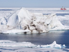 An iceberg floating in Baffin Bay above the Arctic Circle dwarfs the Canadian Coast Guard icebreaker Louis S. St-Laurent on July 10, 2008.