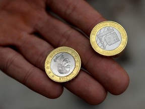 A man shows new one Bolivar coins in downtown Caracas, Venezuela on Tuesday, Aug. 21, 2018.