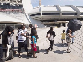 A group of asylum seekers leave Olympic Stadium to go for a walk, in Montreal on Wednesday, August 2, 2017. A long-promised triage system aimed at redirecting irregular border crossers from crowded shelters in Montreal and Toronto will not be in place until as late as the end of September.
