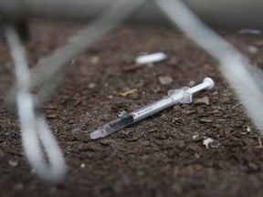 A discarded needle, with blood in it, sits just behind a fence at the Victoria St. safe injection site in Toronto. (Jack Boland/Toronto Sun files)
