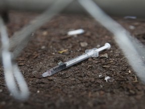 A discarded needle, with blood in it, sits just behind a fence at the Victoria St. safe injection site. (Jack Boland/Toronto Sun)