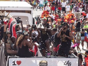 Trinidadian soca performer Machel Montano, right with microphone, sings as his entourage spray champagne during the Scotiabank Toronto Caribbean Carnival grand parade in Toronto on Saturday, August 1, 2015.