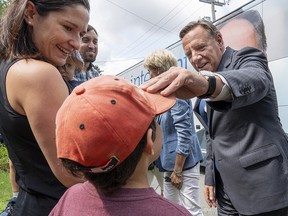 Coalition Avenir Quebec Leader Francois Legault greets Benjamin Menard as his mother Maryse Caron looks on during a campaign stop in Sherbrooke, Que., on Monday, August 27, 2018. (THE CANADIAN PRESS/Paul Chiasson)