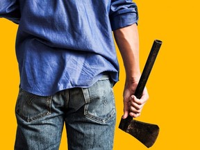 A guy holding old rusty axe, close up rear view, on yellow background with copy space