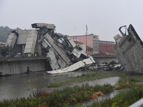 Rescuers work among the rubble of the collapsed Morandi highway bridge in Genoa, northern Italy, Tuesday, Aug. 14, 2018. A large section of the bridge collapsed over an industrial area in the Italian city of Genova during a sudden and violent storm, leaving vehicles crushed in rubble below. (Luca Zennaro/ANSA via AP)