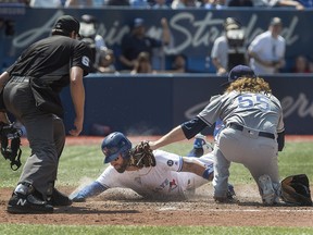 Umpire Ryan Additon watches Toronto Blue Jays' Kevin Pillar slide safely into home plate as Tampa Bay Rays pitcher Ryne Stanek tries to make the tag in Toronto on Sunday, August 12, 2018. (THE CANADIAN PRESS/Fred Thornhill)