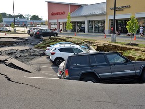Vehicles sit at the bottom of a sinkhole that opened Friday, Aug. 10, 2018, in a parking lot at Tanger Outlets shopping centre in Lancaster, Pa.
