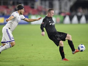 D.C. United forward Wayne Rooney, right, kicks the ball against Orlando City midfielder Dillon Powers, left, during the second half of an MLS soccer match, Sunday, Aug. 12, 2018, in Washington. D.C. United won 3-2. (AP Photo/Nick Wass)
