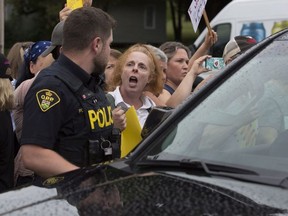 Protesters block Ontario Premier Doug Ford’s car after the buck-a-beer plan announcement at Barley Days brewery in Picton, Ont., on Tuesday Aug. 7, 2018.