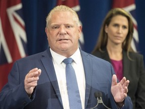Ontario Premier Doug Ford speakws as Ontario Attorney General Caroline Mulroney looks on during a press announcement at the Queens Park Legislature in Toronto on Thursday, August 9, 2018.
