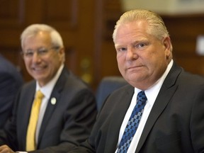Ontario Premier Doug Ford, right, sits with Finance Minister Vic Fedeli and members of cabinet, as they meet with economists from major Canadian banks to discuss the province's economic outlook and the ongoing NAFTA negotiations at Queens Park Legislature, in Toronto on Thursday, August 30, 2018. THE CANADIAN PRESS/Chris Young