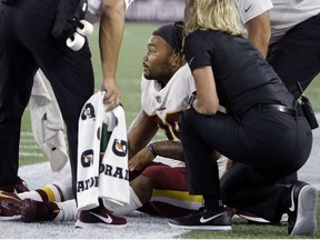 Washington Redskins running back Derrius Guice, center, receives attention on the field after an injury during the first half of a preseason NFL football game against the New England Patriots, Thursday, Aug. 9, 2018, in Foxborough, Mass.