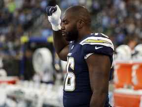 Chargers offensive tackle Russell Okung raises his fist during the playing of the U.S. anthem before the team's preseason game against the Seahawks in Carson, Calif., Saturday, Aug. 18, 2018.