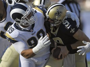 Saints quarterback Drew Brees, right, gets sacked by Rams defensive end Aaron Donald during NFL action in Los Angeles on Nov. 26, 2017.