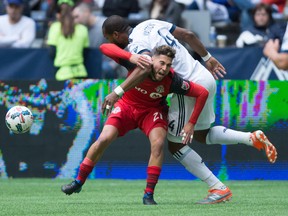 Toronto FC midfielder Jonathan Osorio (21) and Vancouver Whitecaps defender Kendall Waston (4) vie for the ball during a game last season. THE CANADIAN PRESS