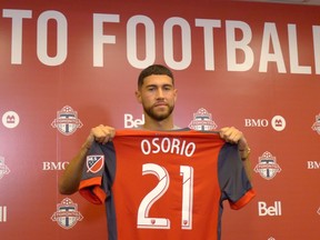 Toronto FC midfielder Jonathan Osorio holds up his jersey at a news conference in Toronto, Thursday, Aug.30, 2018. Osorio, enjoying a career year, has elected to stay with Toronto FC rather than test the waters outside Major League Soccer. THE CANADIAN PRESS/Neil Davidson