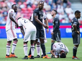 Toronto FC's Marky Delgado (18) kneels on the ground after being tackled by Vancouver Whitecaps' Felipe Martins, not seen, as Kendall Waston, centre, and Cristian Techera, right, look on during first half Canadian Championship soccer final action, in Vancouver on Wednesday, August 8, 2018. THE CANADIAN PRESS/Darryl Dyck