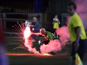 A security guard picks up a flare that was thrown onto the field during second half Canadian Championship soccer action between the Ottawa Fury FC and the Toronto FC, in Ottawa on Wednesday, July 18, 2018. THE CANADIAN PRESS/Justin Tang