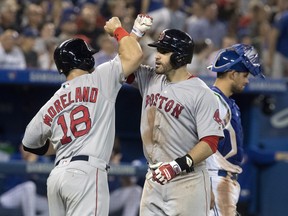 Boston Red Sox' J.D. Martinez is greeted at home plate by teammate Mitch Moreland after he hit a three run home run in the eighth inning against the Blue Jays on Tuesday night at the Rogers Centre. (Fred Thornhill/The Canadian Press)