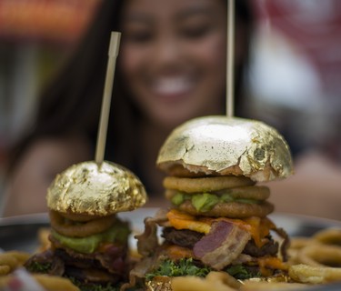 Carmella Dela Cruz, marketing and operations coordinator
with Bacon Nation, with the Golden Burger - from Bacon Nation - with an edible gold bun for $100, and a $24 slider on the left - at the CNE Media Preview at Exhibition Place in Toronto, Ont. on Wednesday August 15, 2018. The Canadian National Exhibition runs from August 17 to September 3. Ernest Doroszuk/Toronto Sun/Postmedia