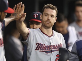 Minnesota Twins' Logan Forsythe is greeted in the dugout after scoring during the sixth inning of a baseball game against the Detroit Tigers, Friday, Aug. 10, 2018, in Detroit. (AP Photo/Carlos Osorio)