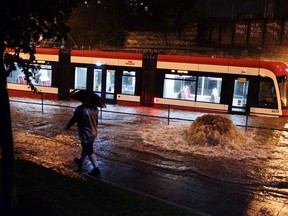 Water overflows from heavy rain, trapping a streetcar on King St. W. in Toronto on Tuesday, August 7, 2018.