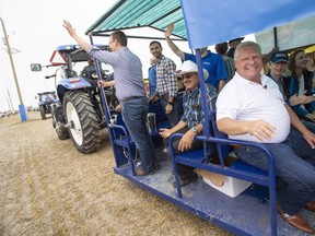 Ontario Premier Doug Ford rides on a wagon with members of his caucus during the opening parade at the International Plowing Match in Pain Court Ont. Tuesday, September 18, 2018. THE CANADIAN PRESS/ Geoff Robins