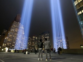 People observe the 'Tribute in Light' atop the Battery Parking Garage as it rises skyward in Lower Manhattan, Sept. 11, 2018 in New York City.