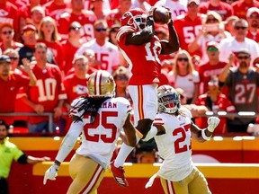 Tyreek Hill #10 of the Kansas City Chiefs leaps in the air to make a catch against Adrian Colbert #27 and Richard Sherman #25 of the San Francisco 49ers during the second quarter fo the game at Arrowhead Stadium on September 23rd, 2018 in Kansas City, Missouri.