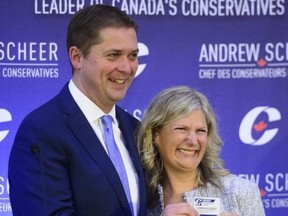 New Conservative MP Leona Alleslev is presented with a party card by Conservative Leader Andrew Scheer as she is welcomed during the conservative caucus meeting on Parliament Hill in Ottawa on Wednesday, Sept. 19, 2018.