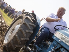 Ontario Premier Doug Ford sits on a Ford tractor as he plows a furrow at the International Plowing Match in Pain Court Ont. Tuesday, September 18, 2018. THE CANADIAN PRESS/ Geoff Robins