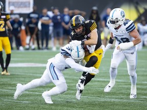 Tiger-Cats wide receiver Luke Tasker (right) is tackled by Argonauts defensive back Alden Darby during Hamilton’s win on Monday.  Peter Power/The Canadian Press