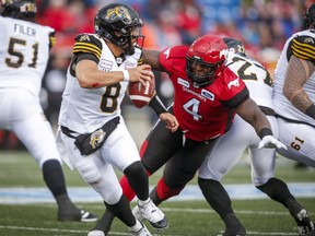 Tiger-Cats quarterback Jeremiah Masoli (left) runs from Stampeders’ Micah Johnson earlier this season. The Ticats offensive line will need to do a better job of protecting their quarterback in the rematch on Saturday.  The Canadian Press