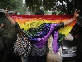 Gay rights activists hold a flag as they celebrate amid heavy downpour after the country's top court struck down a colonial-era law that made homosexual acts punishable by up to 10 years in prison, in New Delhi, India, Thursday, Sept. 6, 2018. (AP Photo/Altaf Qadri)