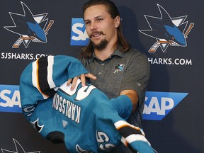 Newly acquired San Jose Sharks defenseman Erik Karlsson puts on jersey during a news conference held by the NHL hockey team in San Jose, Calif., Wednesday, Sept. 19, 2018. (AP Photo/Josie Lepe)