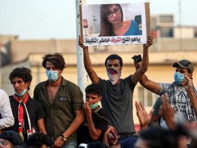 An Iraqi protester holds up a poster with former porn star Mia Khalifa on it. He reckons she could do a better job of running the county.