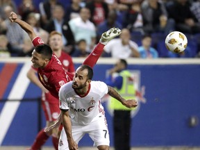 Red Bulls midfielder Sean Davis (left) goes flying while competing for the ball with Toronto FC midfielder Victor Vazquez during the second half in Harrison, N.J., Saturday night.  AP