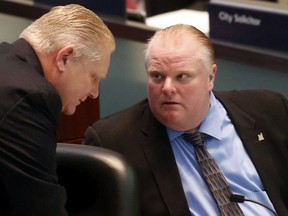 Councillor Doug Ford speaks with Mayor Rob Ford at a meeting of Toronto city council on Monday December 16, 2013. Michael Peake/Toronto Sun/Postmedia Network
